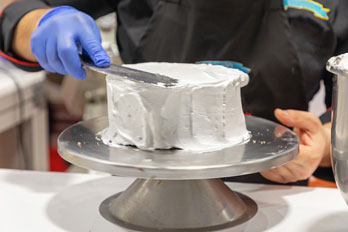 pastry chef using a cake turntable and spatula